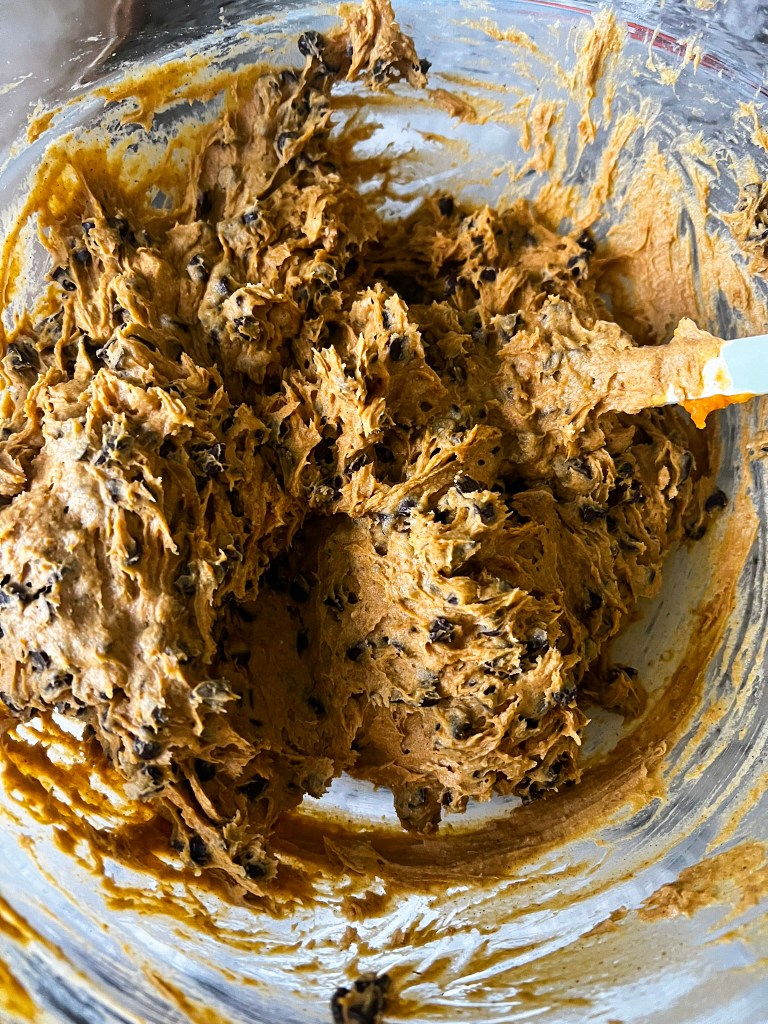 Pumpkin chocolate chip cookie dough mixed and ready in a glass bowl with a spatula.